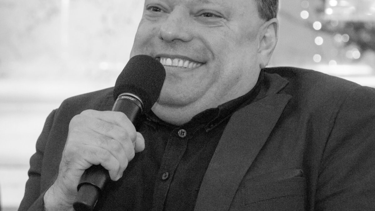 Portrait von Herbert Pichler in Schwarz Weiß, er lächelt und hält ein Mikrofon