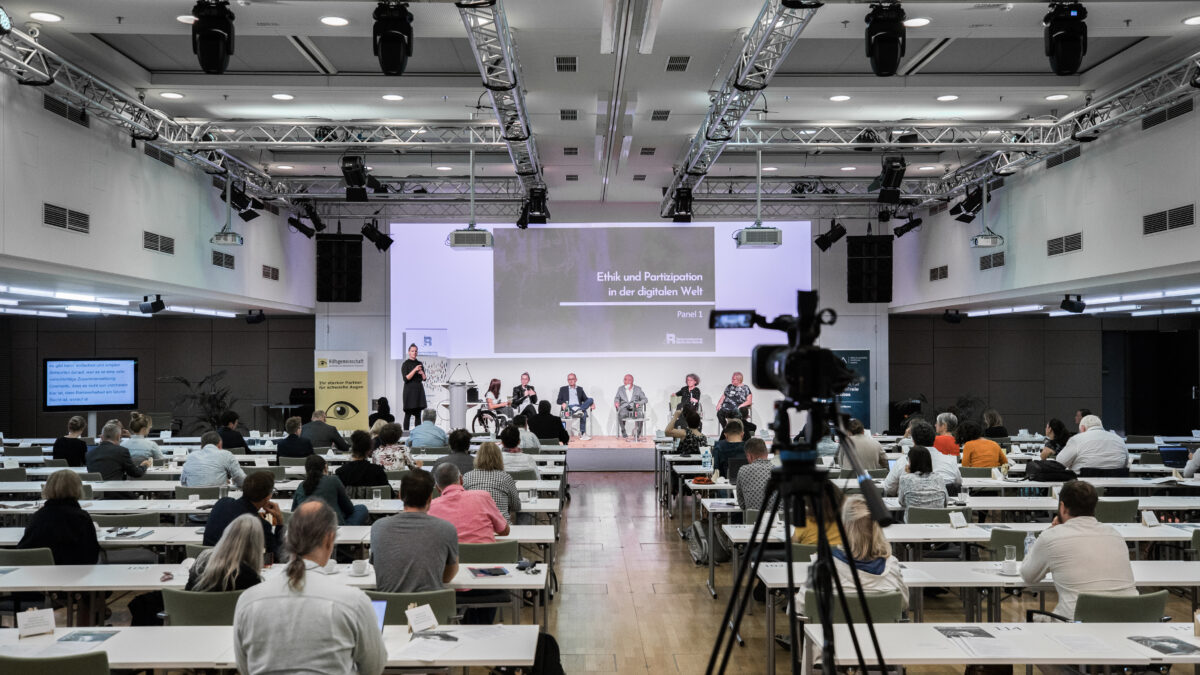 Foto der Konferenz aus dem Zuschauerraum mit Blick auf die Bühne.