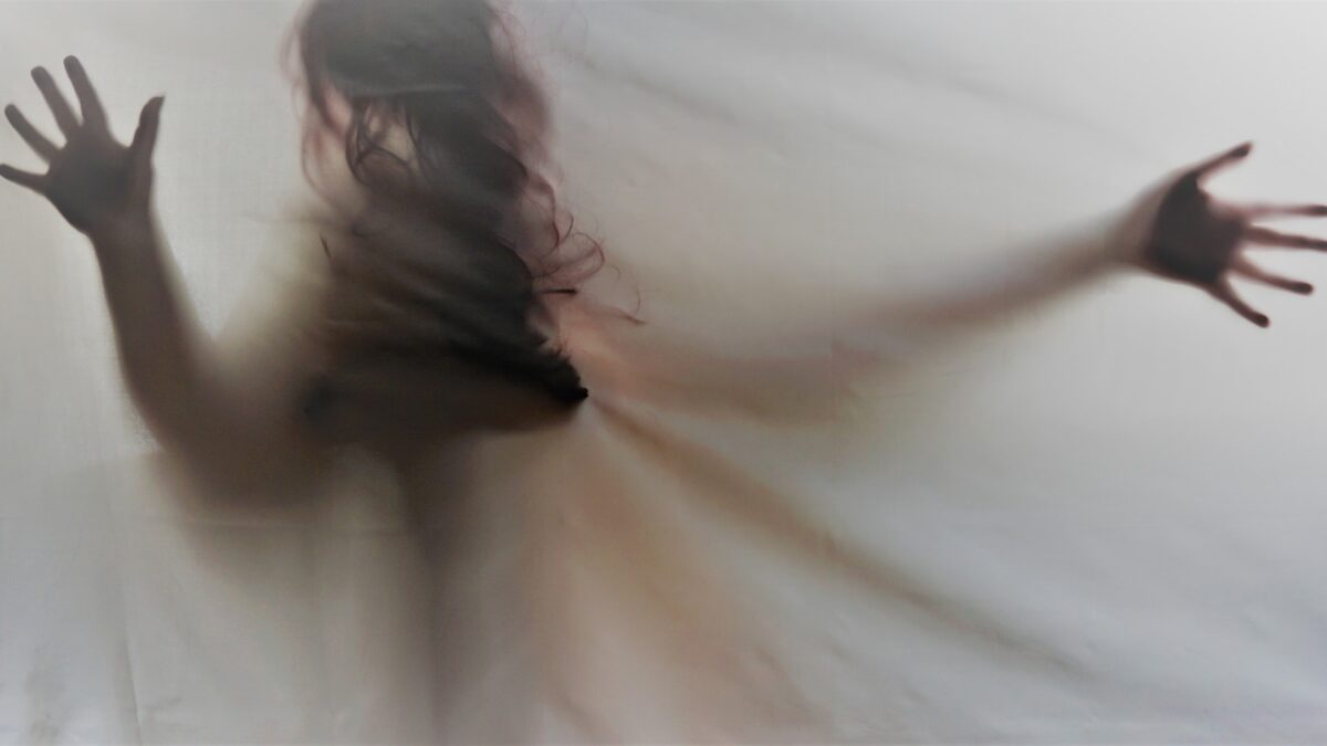 Schatten einer Frau mit langem Haar und Kleid hinter einer Leinwand