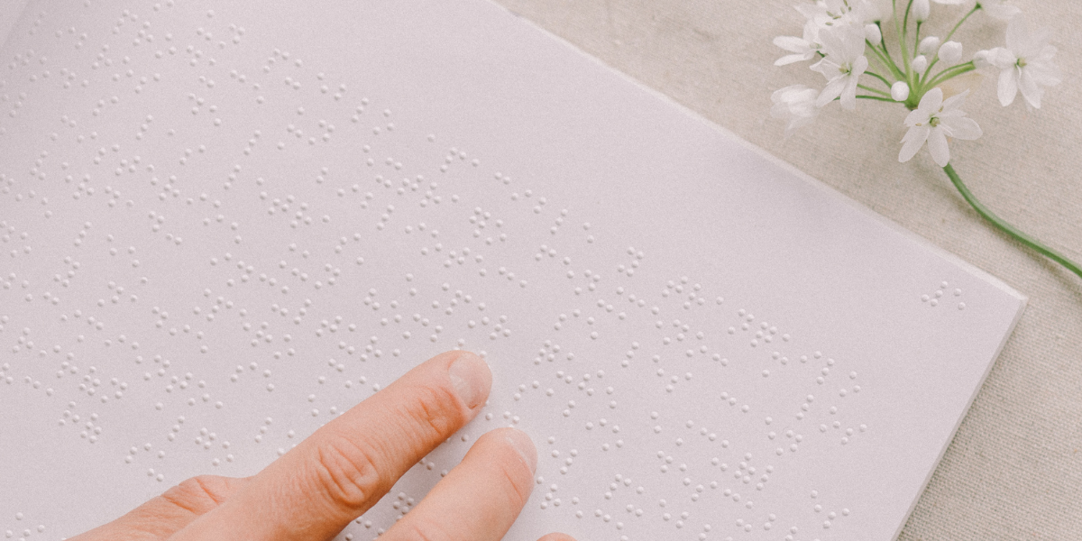Nahaufnahme von Fingern auf einem Papier mit Braille-Schrift