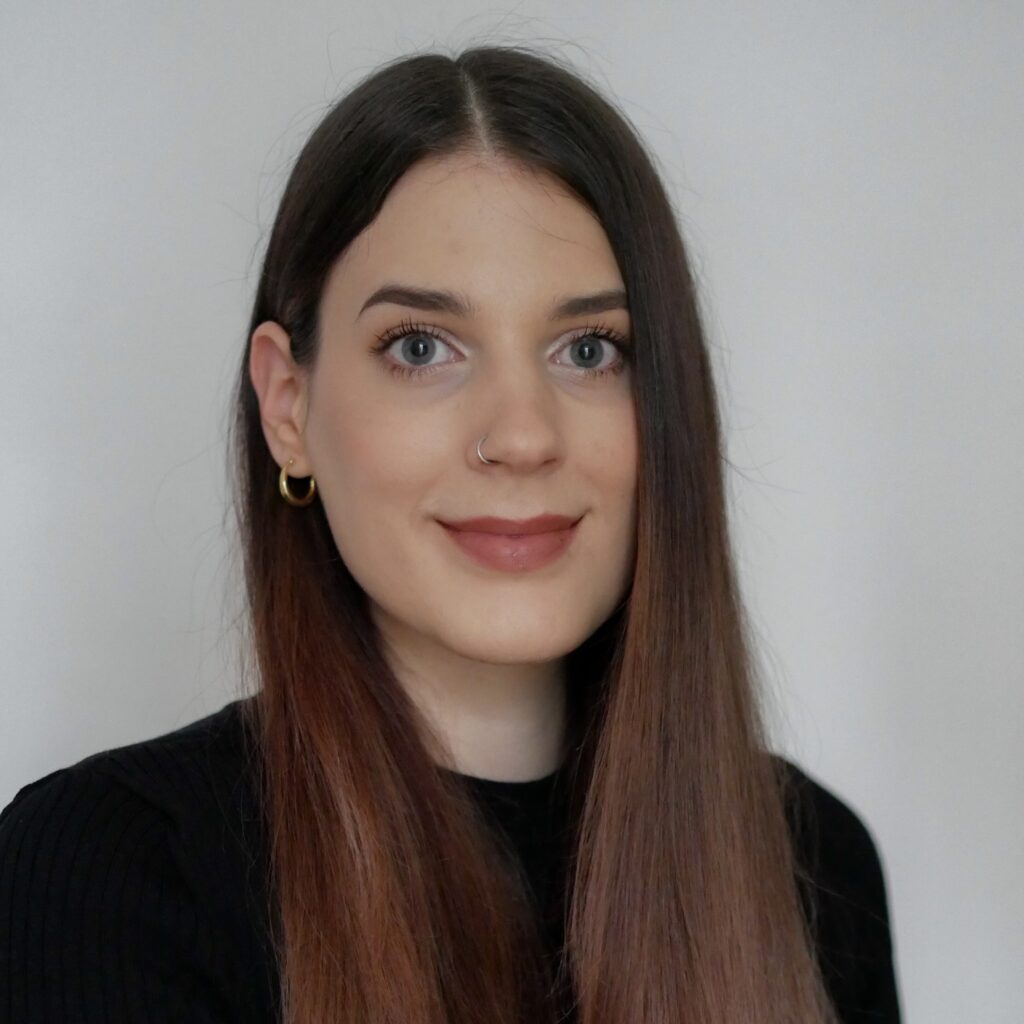 Portrait Andrea Strohriegl, BEd, sie hat lange, rotbraune Haare und trägt einen schwarzen Pulli