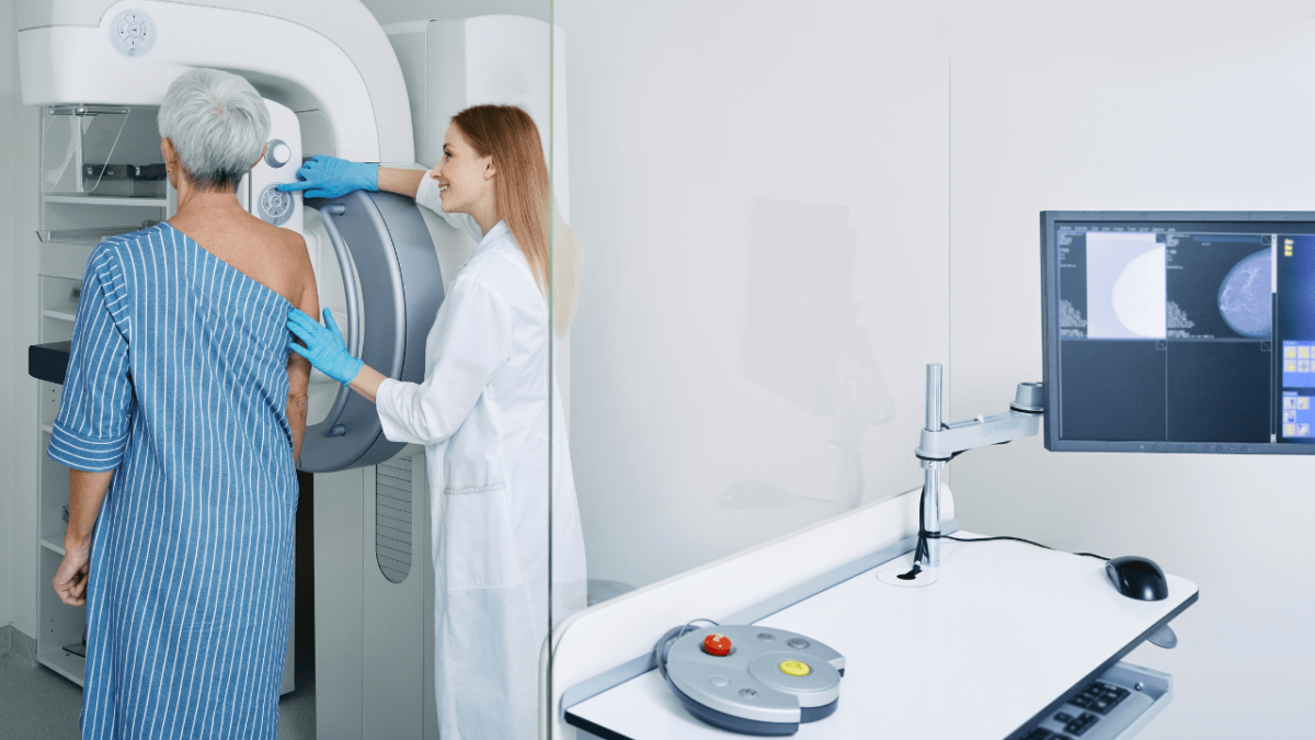 Frau mit radiologisch technischer Assistentin in einem Röntgeninstitut bei einer Mammographie-Untersuchung, Foto: Canva