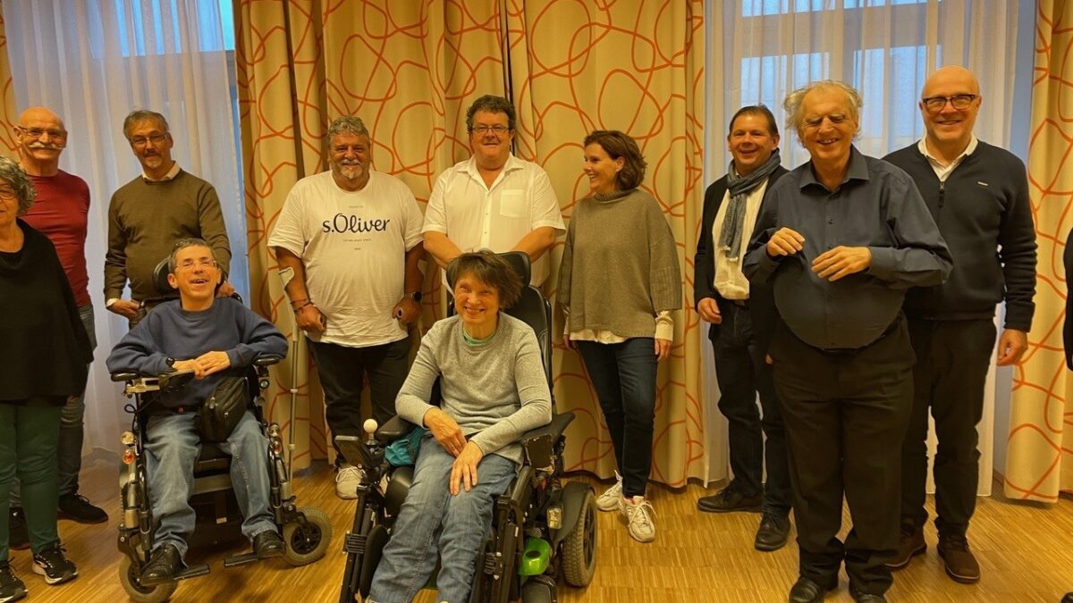 Gruppenbild zeigt 10 nebeneinander sitzende Personen, vorne zwei Personen im Rollstuhl