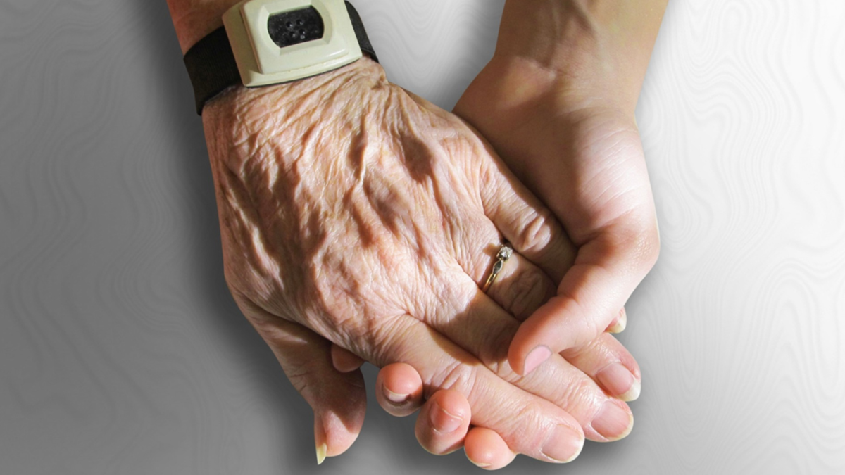 Eine Hand einer älteren Person wird von einer jüngeren Hand gehalten