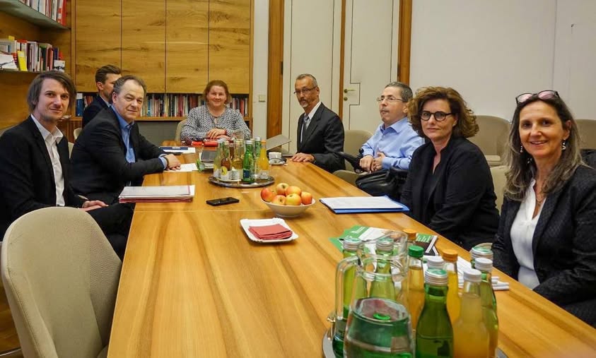 Gruppenbild mehrerer Personen rund um einen braunen Besprechungstisch