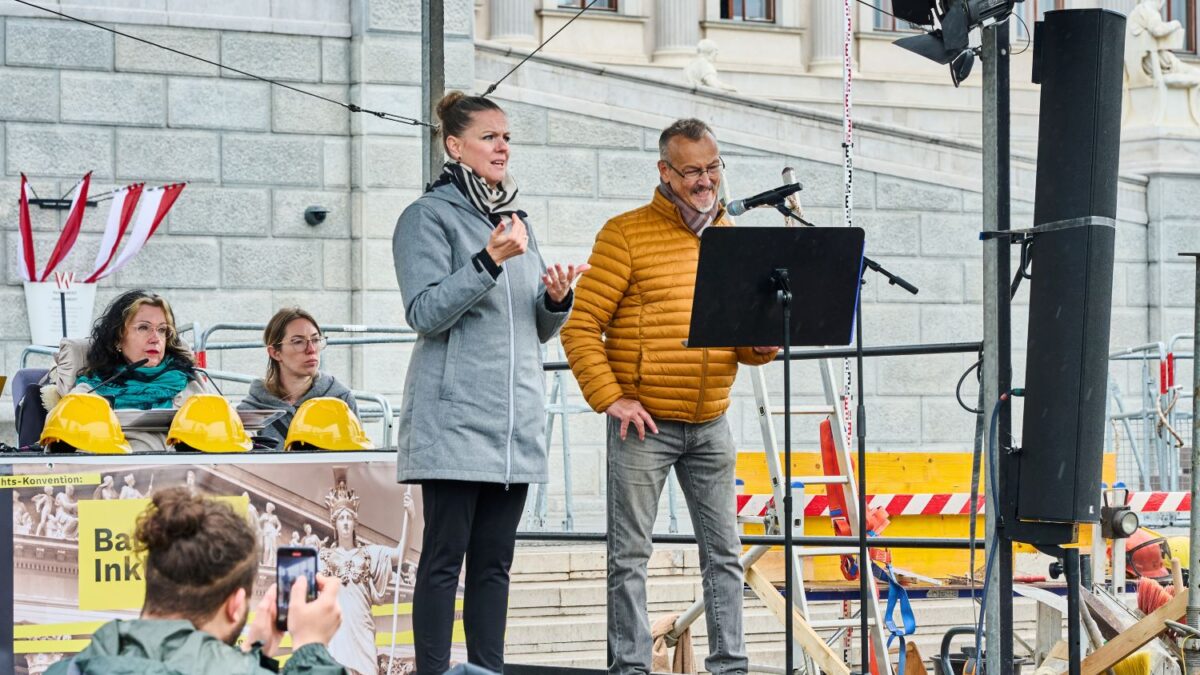 Klaus Widl spricht auf der Bühne bei der Baustelle Inklusion, daneben über setzt eine Gebärdensprachdolmetscherin
