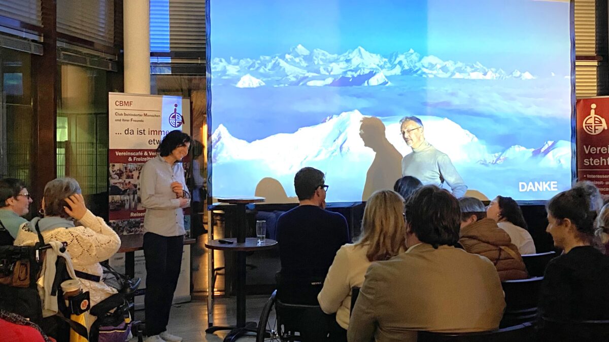 Personen auf Stühlen und in Rollstühlen hören und sehen sich den Multivisions- und Motivationsvortrag von Gerlinde Kaltenbrunner an.