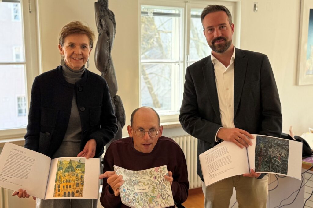 Eine Frau und zwei Männer halten jeweils einen Kunstkatalog in Händen