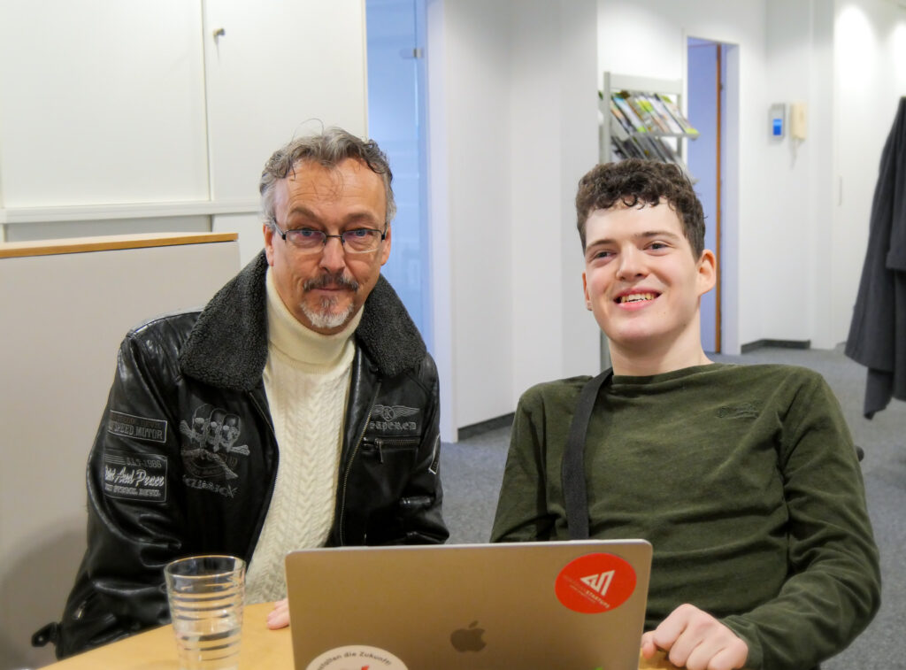 2 Männer sitzen vor einem Laptop