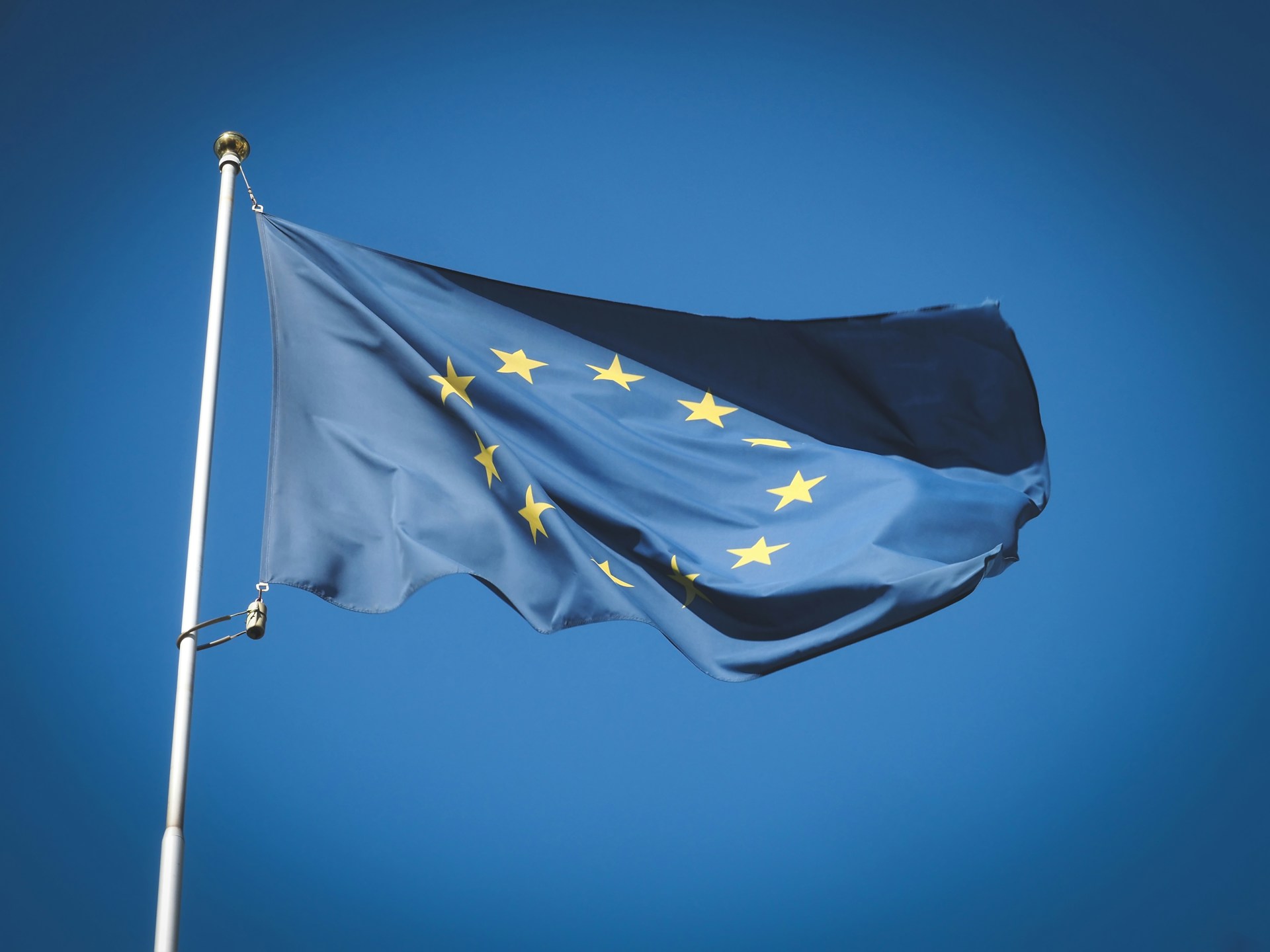 EU-Flagge weht im Wind vor blauem Himmel, Foto: Unsplash/Alexey Larionov