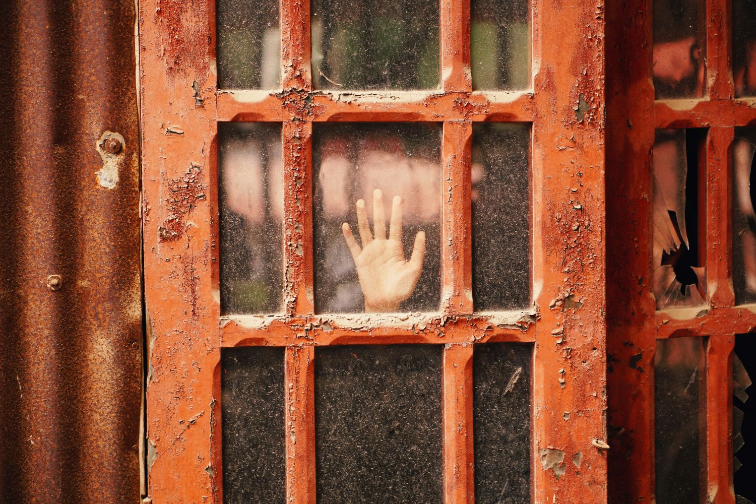 rote Glastür, hinter der eine Hand zu sehen ist
