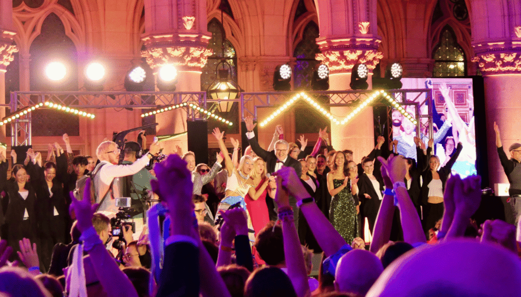Feierliche Eröffnung des Diversity Ball: Die Menschen auf der Bühne und im Publikum heben die Hände und jubeln