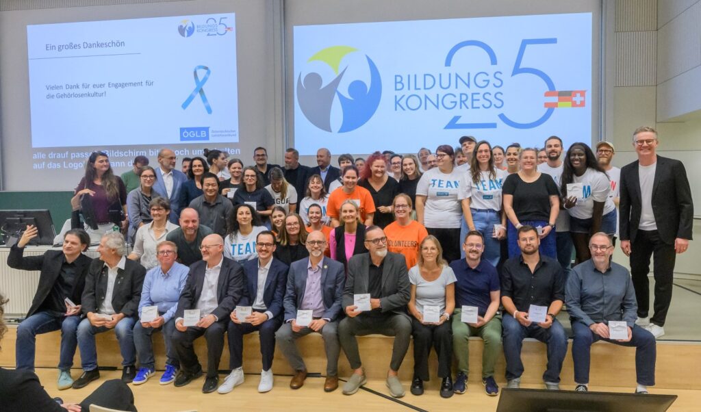 Gruppenfoto zahlreicher Personen auf einer Bühne, Im Hintergrund Screen mit Sujet des Bildungskongresses