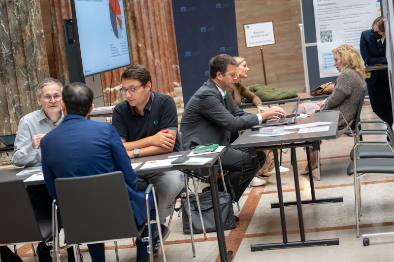 an Tischen sitzende Personen in der Säulenhalle des Parlaments