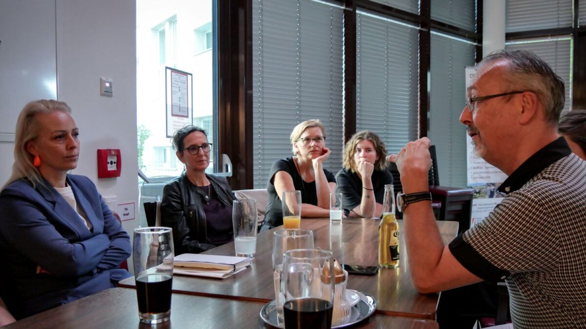 mehrere Personen sitzen an einem Tisch und unterhalten sich