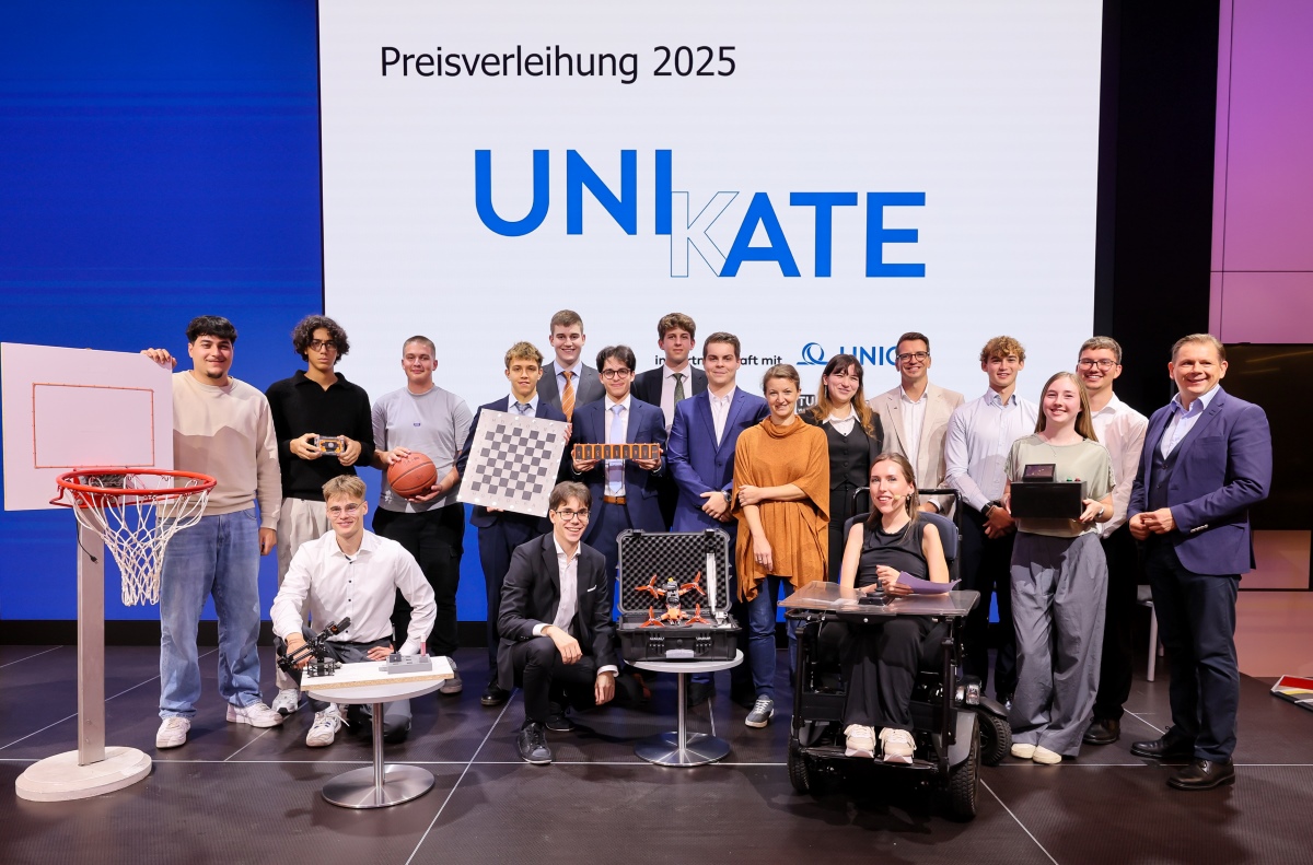Gruppenfoto von 18 Personen, die auf einer Bühne vor einem Screen mit dem Logo "UNIKATE" stehen. Zwei dieser Personen knien, eine sitzt im Rollstuhl. Alle Schüler präsentieren ihre Unikate