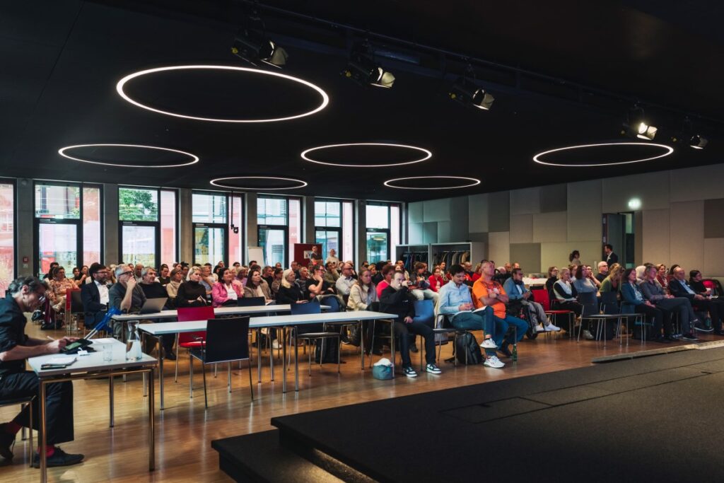 Viele Menschen sitzen in einem Veranstalttungssaal