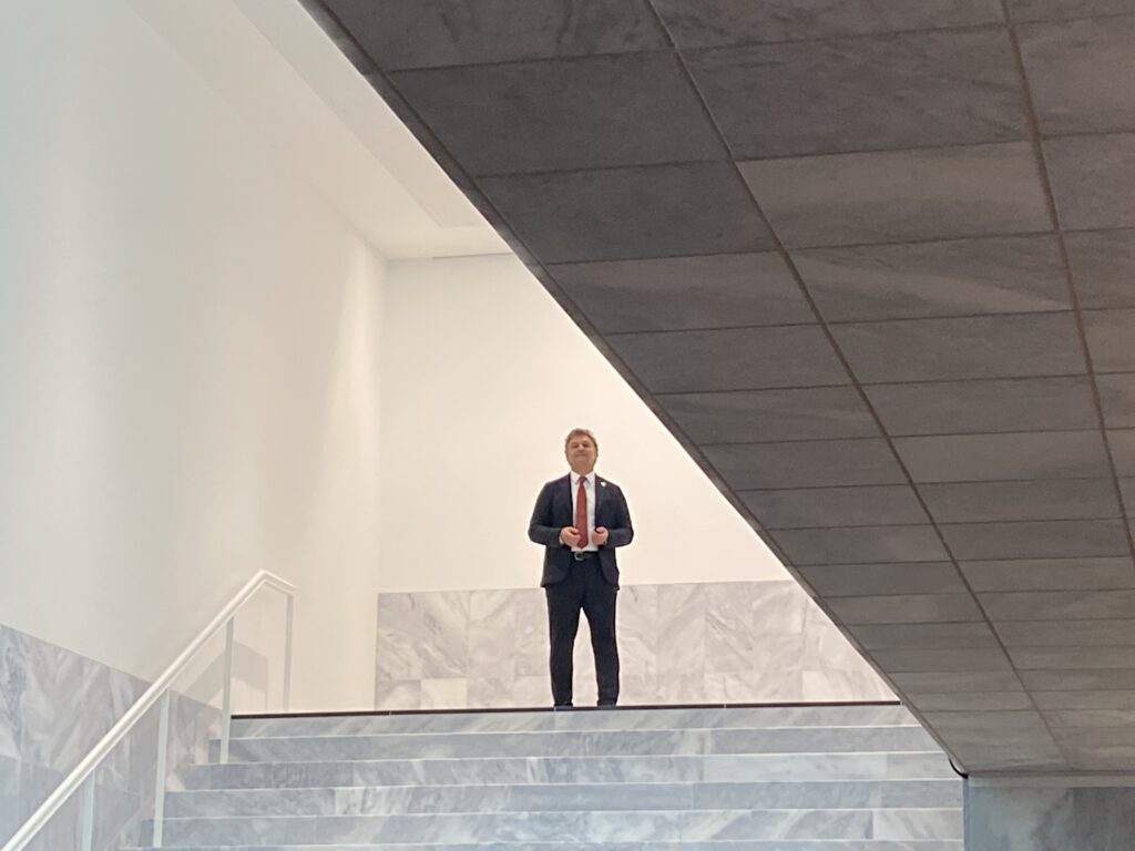 Mann in schwarzem Anzug steht auf einer Treppe und singt