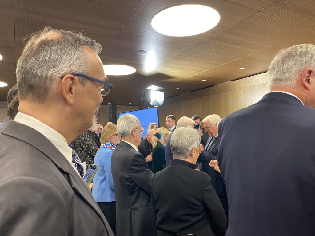 festlich gekleidete Personen stehen in einem Festsaal