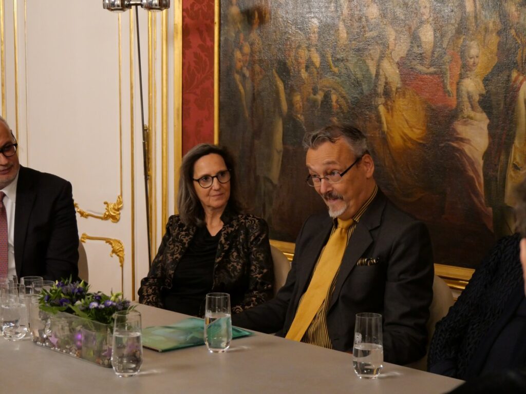 3 Personen sitzen rund um einen Besprechungstisch im Arbeitszimmer von Bundespräsident Dr. Alexander Van der Bellen