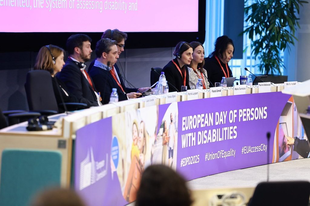 Podium, hinter dem mehrere Personen sitzen