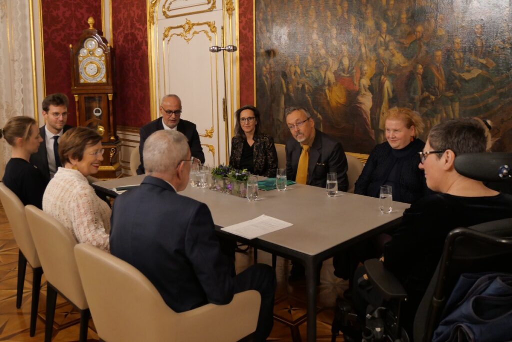 10 Personen sitzen rund um einen Besprechungstisch im Arbeitszimmer von Bundespräsident Dr. Alexander Van der Bellen