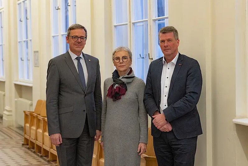 2 Männer und eine Frau stehen elegant gekleidet nebeneinander