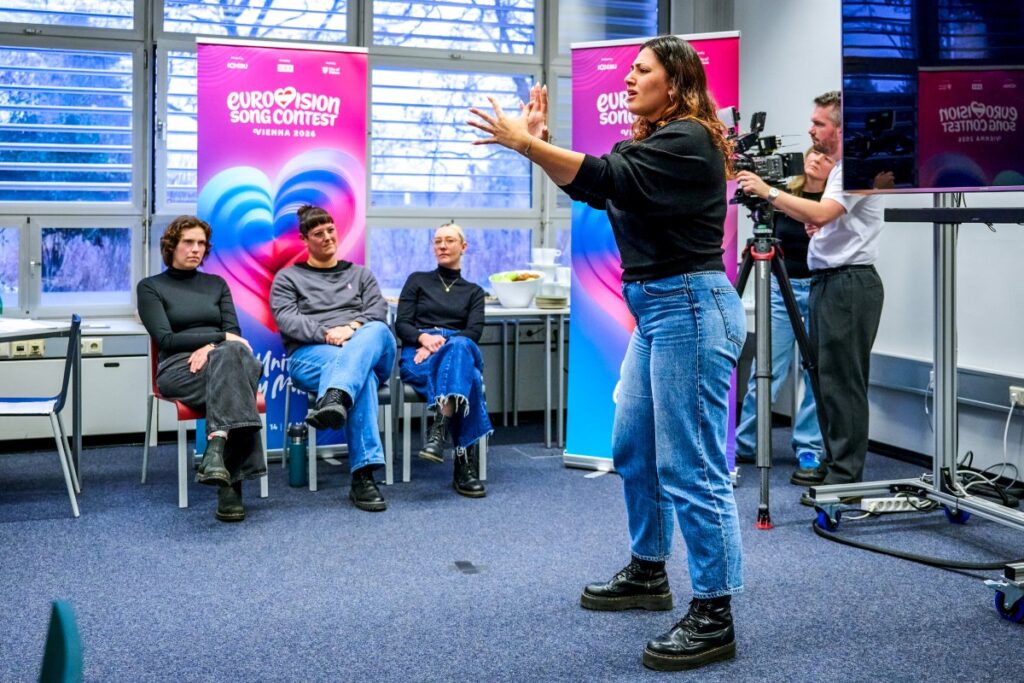 junge Frau performt in Gebärdensprache, im Hintergrund sitzt die Jury