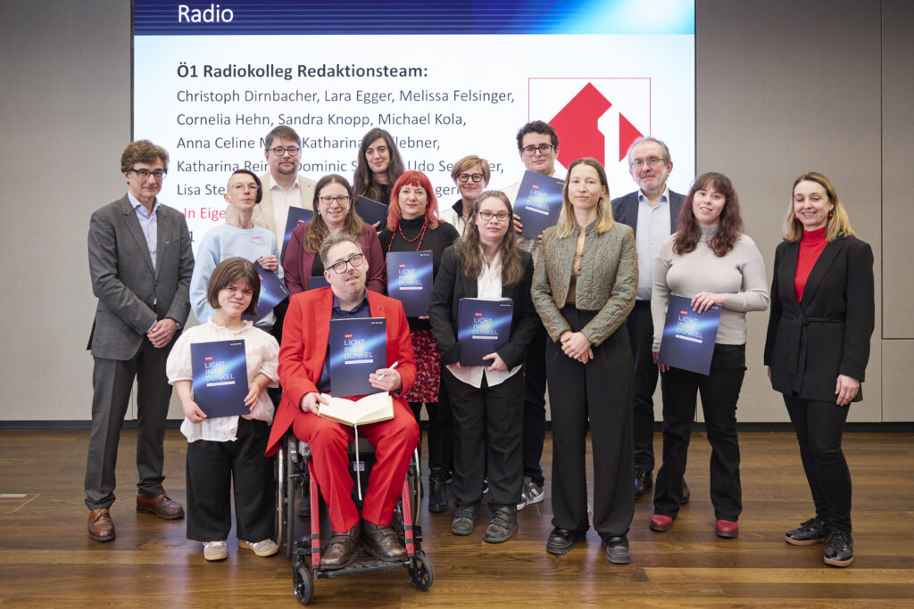 Gruppenfoto des Ö1 Radiokolleg Redaktionsteams als Preisträger*innen des Herbert-Pichler-Inklusions-Medienpreises 2026 in der Kategorie Radio. Mehrere Personen stehen und sitzen auf einer Bühne, einige halten ihre Auszeichnungen. Im Hintergrund ist eine Präsentationsfolie mit dem Titel der Sendereihe und den Namen des Teams zu sehen.
