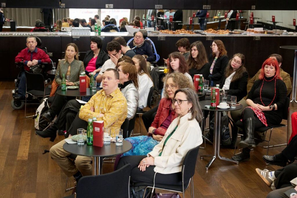 Mehrere Personen sitzen in einem Raum bei der Verleihung des Herbert Pichler-Inklusions-Medienpreises