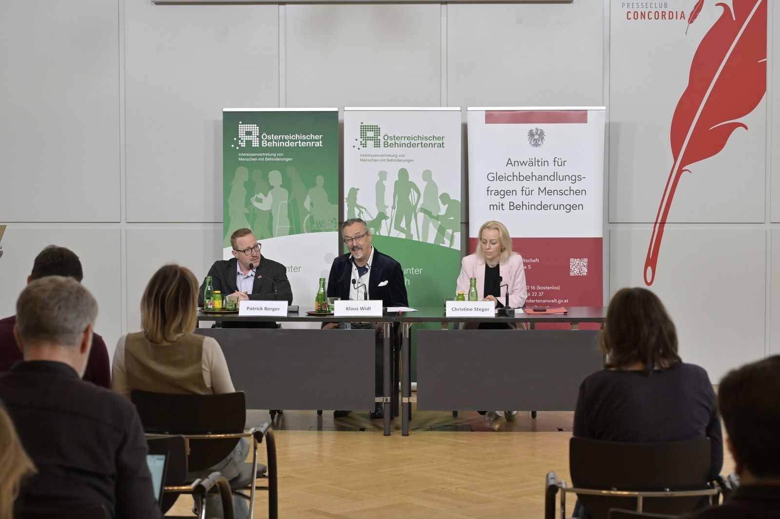 Patrick Berger, Klaus Widl und Christine Steger am Podium vor Roll-ups des Österreichischen Behindertenrats bei der Pressekonferenz zum Ausgleichstaxfonds.