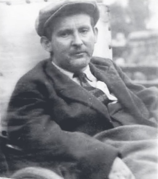 Schwarz-weiß-Porträt von Siegfried Braun. Der Mann sitzt und blickt in die Kamera. Er trägt eine Schiebermütze, Jackett und Hemd.