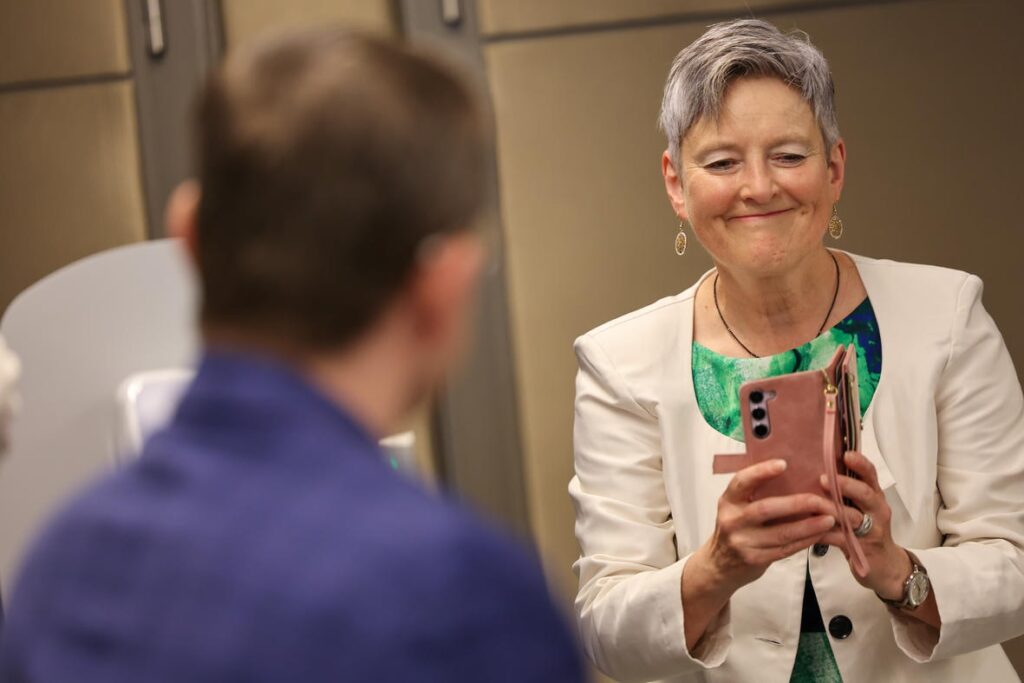 Eine Frau fotografiert bei der Jubiläumsfeier „50 Jahre Österreichischer Behindertenrat“ mit ihrem Smartphone.
