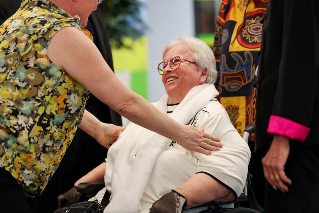 Eine Frau im Rollstuhl spricht bei der Jubiläumsfeier „50 Jahre Österreichischer Behindertenrat“ mit anderen Gästen.