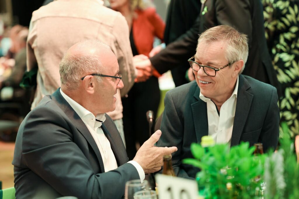 Zwei Gäste unterhalten sich bei der Jubiläumsfeier des Österreichischen Behindertenrats an einem festlich gedeckten Tisch.