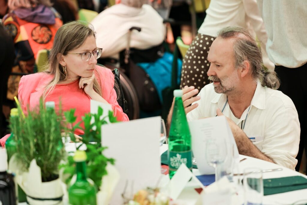 Jasna Puscaric und Emil Benesch sprechen bei der Jubiläumsfeier des Österreichischen Behindertenrats an einem gedeckten Tisch.