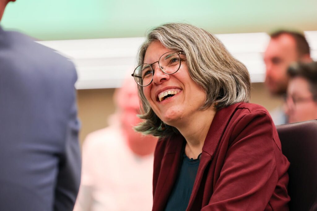 Eine Frau mit Brille und rotem Blazer lacht bei der Jubiläumsfeier des Österreichischen Behindertenrats.