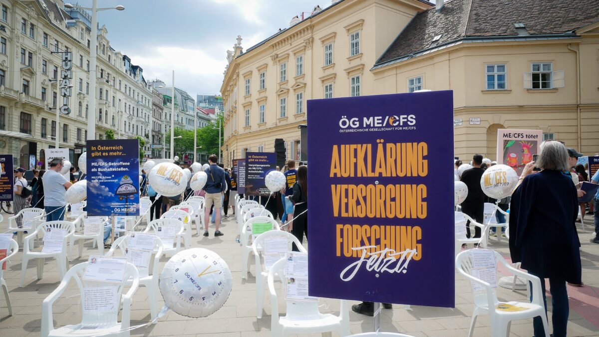 Foto der Aktion am Heldenplatz. Es sind Sessel aufgestellt, an denen Botschaften und Luftballons befestigt sind. Im Vordergrund ein Schild mit der Aufschrift "Aufklärung, Versorgung, Forschung. Jetzt"