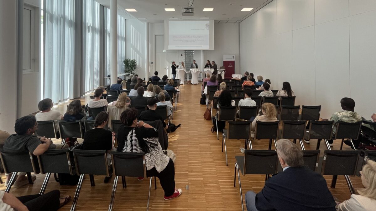 Sitzungssaal mit zahlreichen Personen von hinten fotografiert