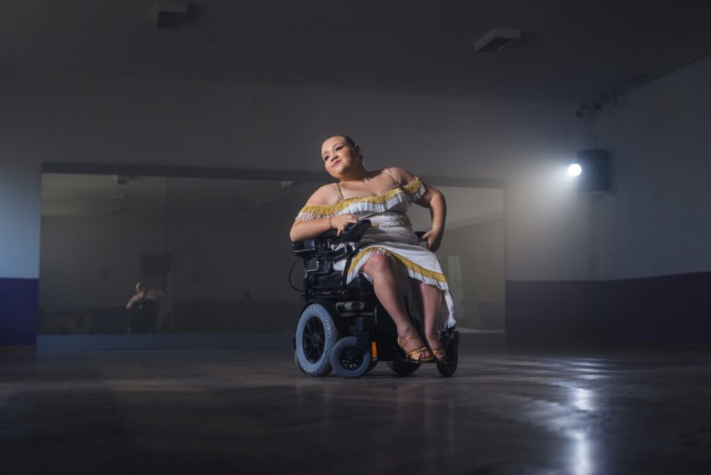 Rollstuhlnutzerin im Tanoutfit tanzt in einem Tanzstudio