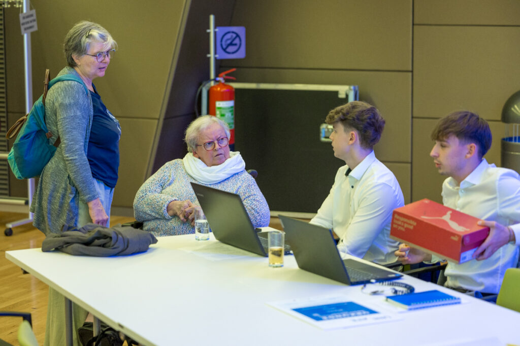 Emilie Karall und ihre Assistentin unterhalten sich mit 2 Schülern, die eine Innovation präsentieren