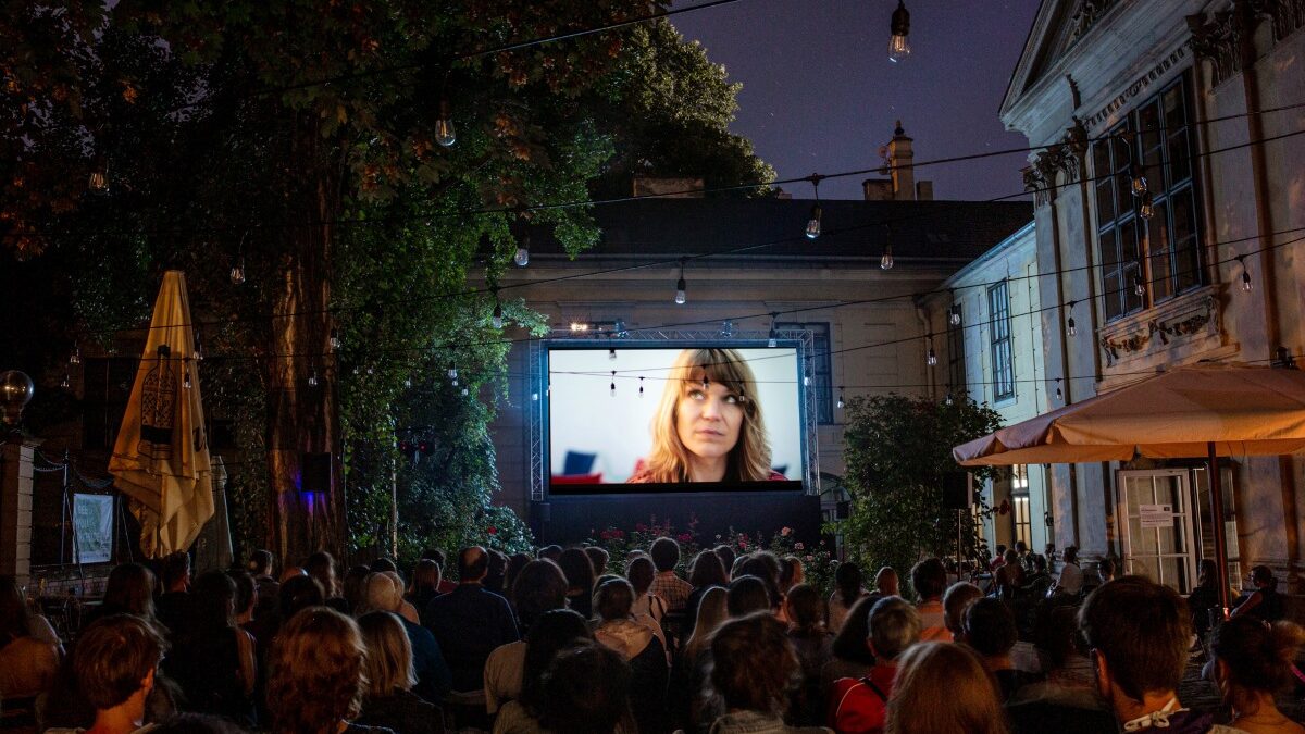 Open-Air-Kino beim Kurzfilmfestival dotdotdot: Publikum sitzt abends im Innenhof vor einer großen Leinwand.