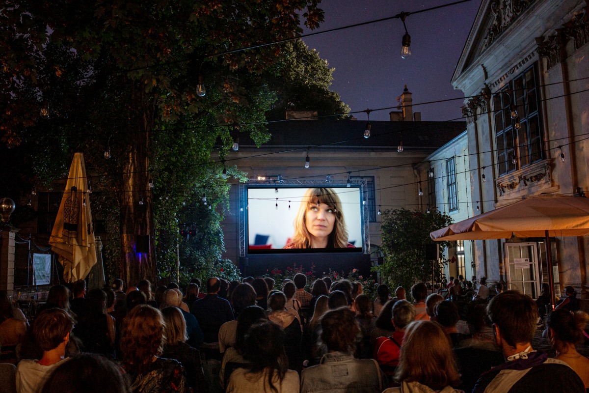 Open-Air-Kino beim Kurzfilmfestival dotdotdot: Publikum sitzt abends im Innenhof vor einer großen Leinwand.
