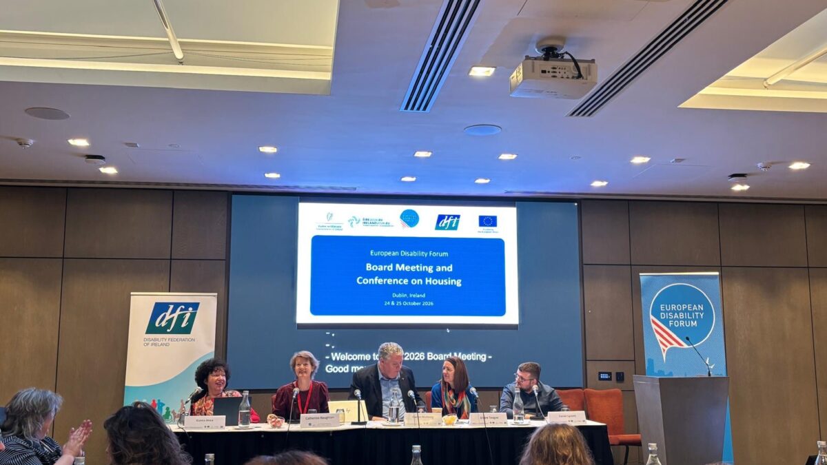 5 Personen sitzen an einem Podium und sprechen vor einem Publikum. Im Hintergrund der Titel: "Board Meeting and Conference on Housing".