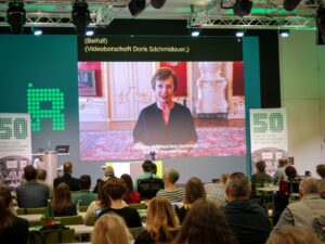 Die Videobotschaft von Doris Schmidauer wird im Saal gezeigt.