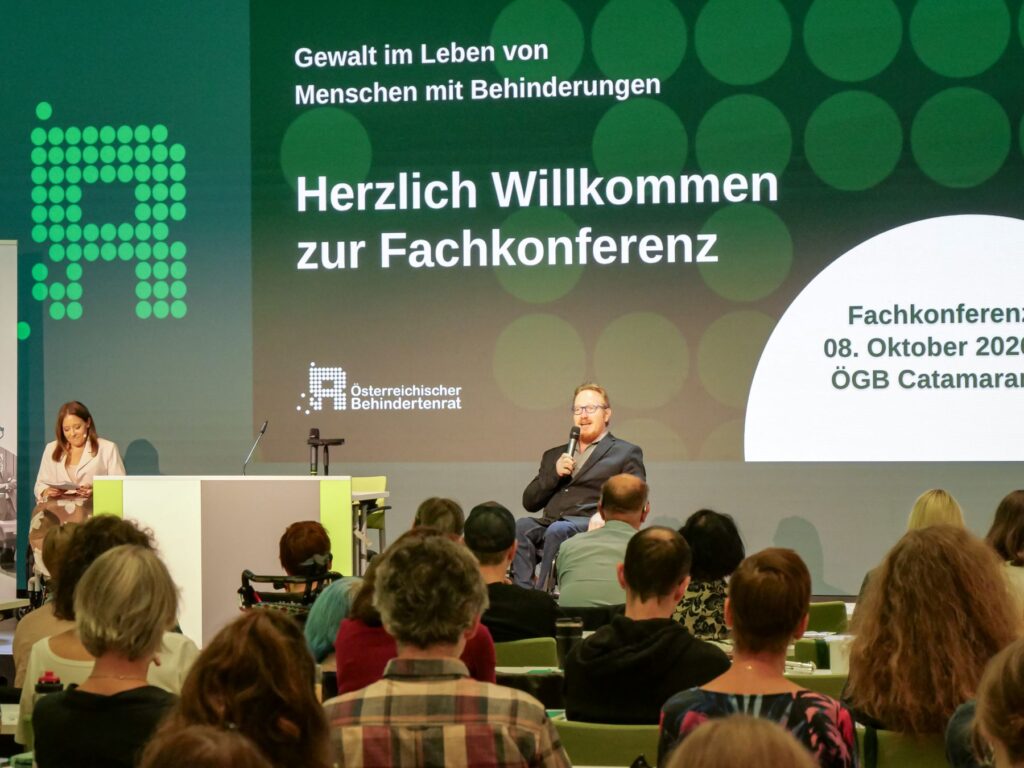 Ein Mann im Rollstuhl spricht auf der Bühne.