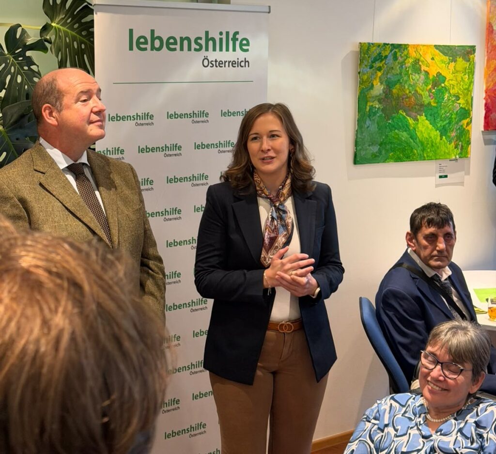 Mehrer Personen stehen nebeneinander, eine Frau sitzt in einem Rollstuhl