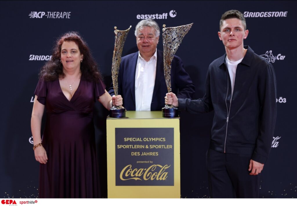 Bianca Maier im violetten Kleid und Silvio Gorsche im dunklen Anzug stehen mit ihren NIKI-Trophäen neben Werner Kogler. Zwischen ihnen befindet sich ein Podest mit der Aufschrift „Special Olympics Sportlerin & Sportler des Jahres“. © GEPA pictures/Sporthilfe